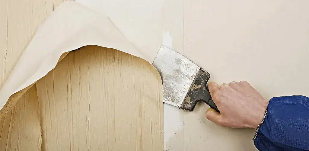 Handyman removing wallpaper with a scraper for wall preparation in Cleveland, OH
