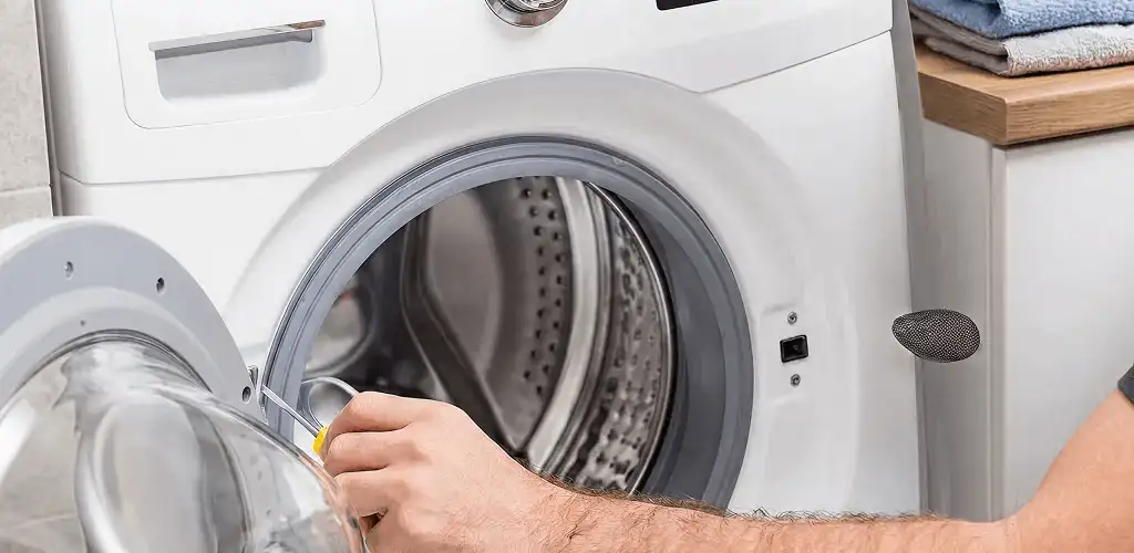 Handyman repairing a front-load washing machine and inspecting the drum in Cleveland, OH