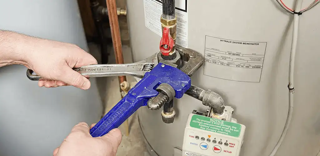 Water heater repair technician tightening the shutoff valve and supply line in Cleveland, OH